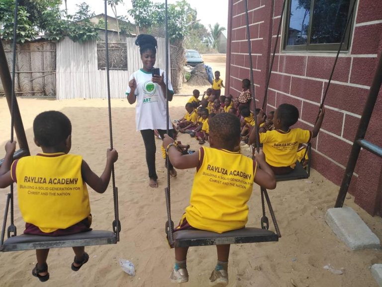 Children in yellow tops playing on swings at the school