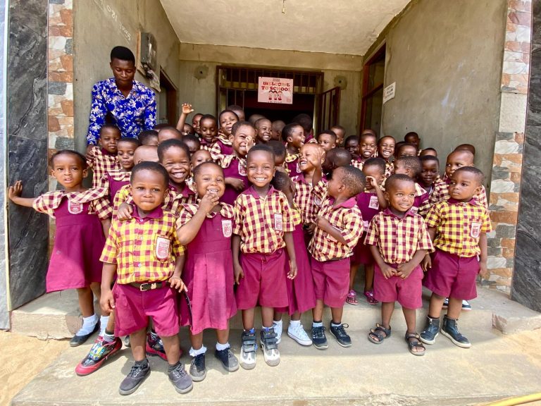 Pupils in maroon and gold uniforms gathered at the school entrance