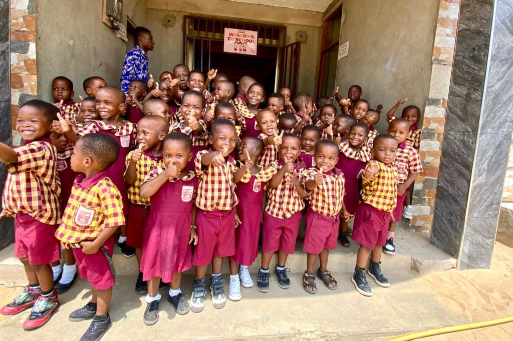 Rayliza Academy pupils in maroon and gold check uniforms gathered together at the school entrance