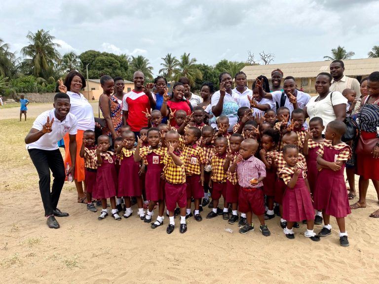 A large group of Rayliza Academy pupils and teachers gathered together outdoors on the school grounds
